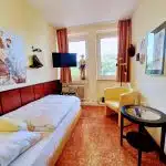 Kleines Einzelzimmer mit Bett, Sessel Tisch, TV mit Bonanza Bildern und Gegenständen Lünen Hotel am Lippepark